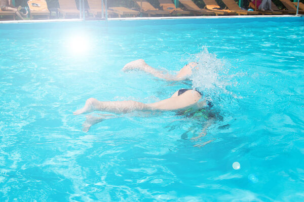 Дети подростки весело плавают и ныряют в открытом бассейне, ноги вверх над водой, брызги, солнечный свет, блики, летний день
