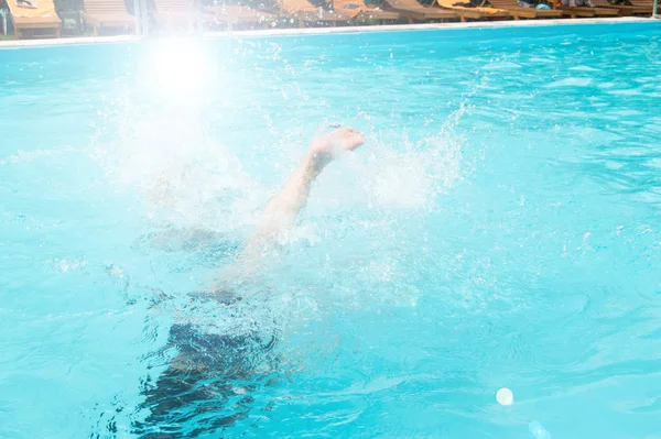 Niños niñas adolescentes se divierten nadando y buceando en la piscina al aire libre, pies sobre el agua, salpicaduras, luz solar, deslumbramiento, día de verano —  Fotos de Stock