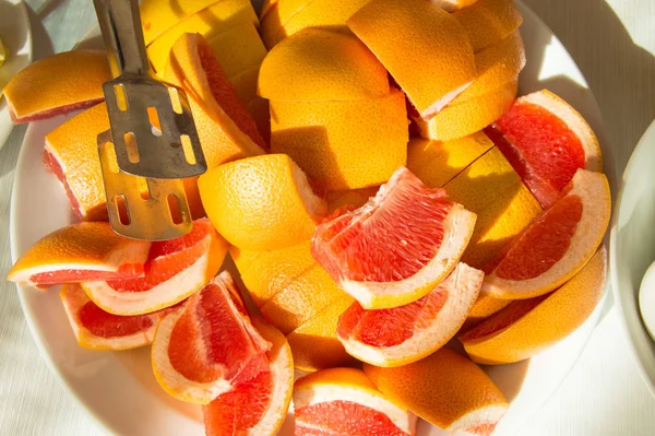 Conceito de café da manhã no hotel, restaurante, fatias recém-cortadas de toranja suculenta, um grande prato de frutas tropicais, luz solar — Fotografia de Stock