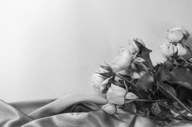 Black-and-white photo, a bouquet of roses on soft silk, flat bed, top view, ready-made layout, romance and love