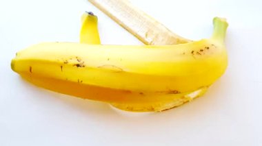 Banana peel on a white background with bright sunlight, a woman's hand puts the peel on the table