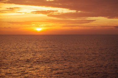 Güzel altın gün batımı denizde, güneş ufukta batıyor, bulutlar gökyüzünde.