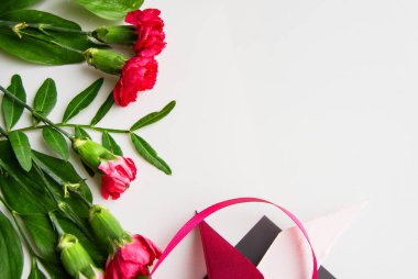 Bahar kompozisyonu ve kırmızı çiçekli düzen, pembe kurdeleler, boşluğun kopyası, düz beyaz izole bir zemin üzerinde yatıyordu. Sevgililer Günü ya da düğün konsepti ve tebrik kartı tasarımın için.