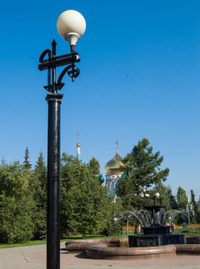 Yazın fıskiyenin ve kilisenin arka planında fener..