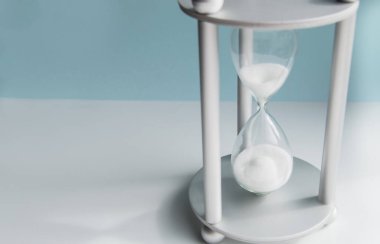 Mavi arka planda kum saati. İş dünyasında zaman yönetimi, teslim tarihi ve denge kavramı.