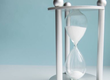 Mavi arka planda kum saati. İş dünyasında zaman yönetimi, teslim tarihi ve denge kavramı.