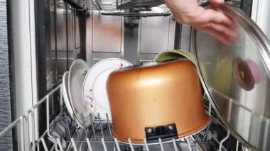 Ev kadınlarının elleri, modern bir bulaşık makinesi kullanarak bulaşık makinesinden temiz bulaşıkları çıkarır, yakın plan. Modern ev aletleri. 4K video