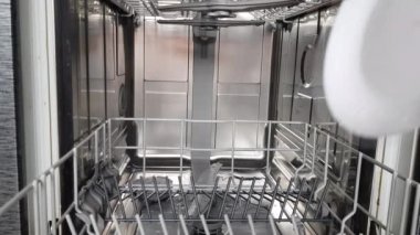 Ev hanımının elleri, modern bir bulaşık makinesi kullanarak bulaşık makinesine kirli bulaşıkları koyuyordu. Modern ev aletleri. 4K video