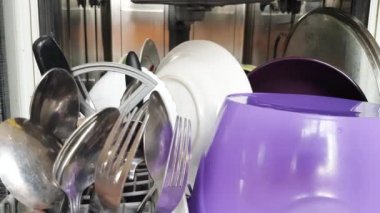 Ev hanımının elleri, modern bir bulaşık makinesi kullanarak bulaşık makinesinden temiz bulaşıkları çıkartıyor. Modern ev aletleri. 4K video