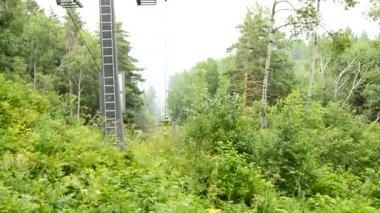 Bulutlu hava ve siste teleferikle dağdan inen ağaçlar boyunca geçilemez bir çalılıkta yavaş hareket eden Altai, Rusya, HD video.