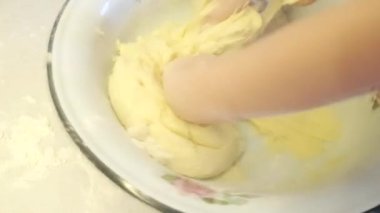 Komik 4K video hamuru bir çocuğun eline yapışır, küçük bir çocuk ekmek hamurunu elle yoğurur ve metal bir kaseye karıştırır. Kase masada hareket ediyor, espri anlayışı.