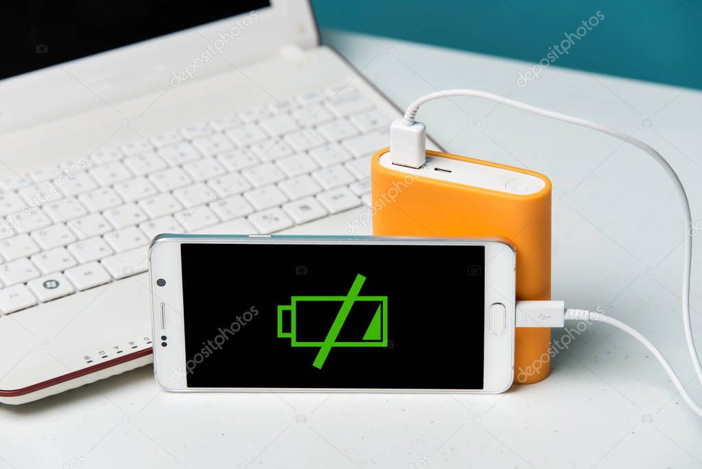 A smartphone with the power bank in the foreground of the camera. Nescessity to take a charger with the phone with a weak battery