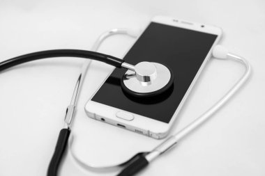 Mobil bir akıllı telefon, beyaz arka plan üzerinde izole kompozisyon yüzey üzerinde sağlık stetoskop aracı. Seçici odak ile