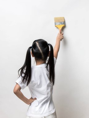 Küçük kız duvar arka plan üzerinde boyama fırça kullanarak çizim