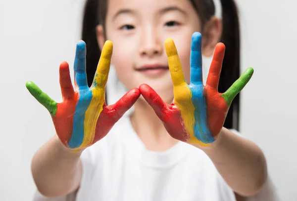 Little Asian girl with hands painted in colorful paints. — Stock Photo, Image