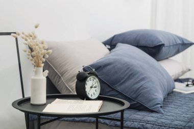 Çalar saat ve vazo ve kitap, yatak ile arka plan. Konsept fotoğraf