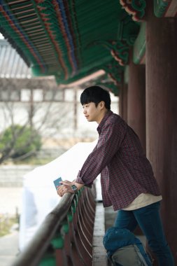 Kore geleneksel evde bir sırt çantasıyla yolculuk yapan bir genç erkek.