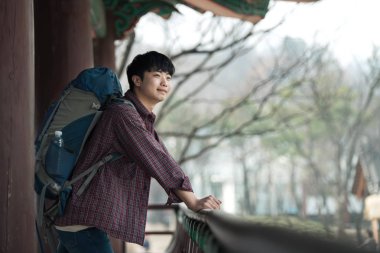 Kore geleneksel evde bir sırt çantasıyla yolculuk yapan bir genç erkek.