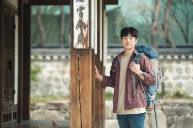 Kore geleneksel evde bir sırt çantasıyla yolculuk yapan bir genç erkek.