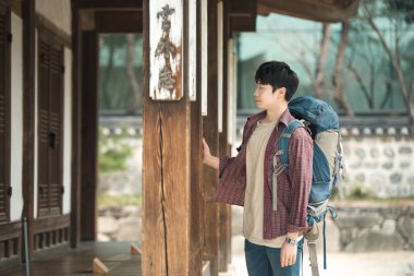 Kore geleneksel evde bir sırt çantasıyla yolculuk yapan bir genç erkek.