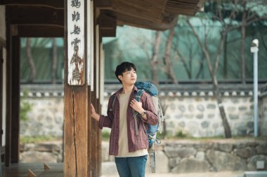 Kore geleneksel evde bir sırt çantasıyla yolculuk yapan bir genç erkek.