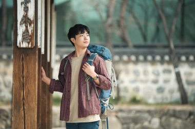 Kore geleneksel evde bir sırt çantasıyla yolculuk yapan bir genç erkek.