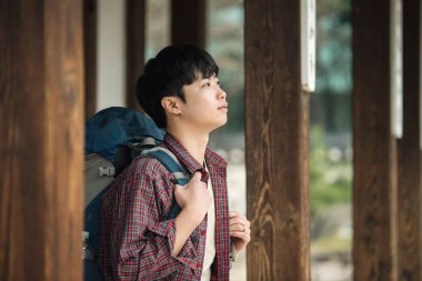 Kore geleneksel evde bir sırt çantasıyla yolculuk yapan bir genç erkek.