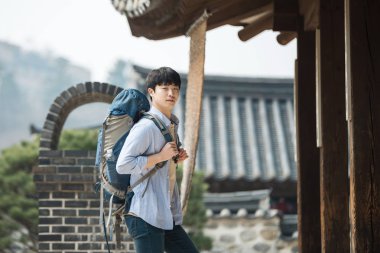 Kore geleneksel evde bir sırt çantasıyla yolculuk yapan bir genç erkek.