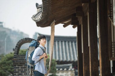 Kore geleneksel evde bir sırt çantasıyla yolculuk yapan bir genç erkek.