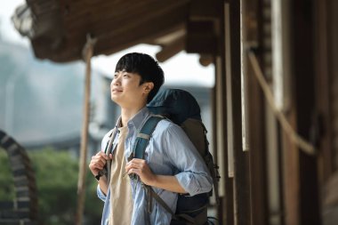 Kore geleneksel evde bir sırt çantasıyla yolculuk yapan bir genç erkek.