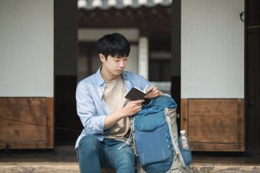 Kore'ye seyahat genç bir adam. bir dinlenme alarak ve pasaportunu izlerken.