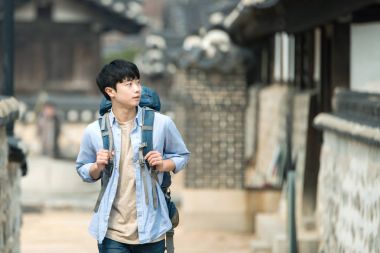 Kore geleneksel evde bir sırt çantasıyla yolculuk yapan bir genç erkek.