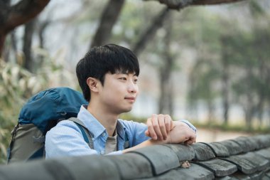 Kore geleneksel evde bir sırt çantasıyla yolculuk yapan bir genç erkek.