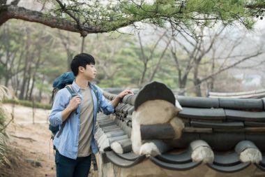 Kore geleneksel evde bir sırt çantasıyla yolculuk yapan bir genç erkek.