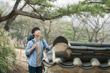 Kore geleneksel evde bir sırt çantasıyla yolculuk yapan bir genç erkek.