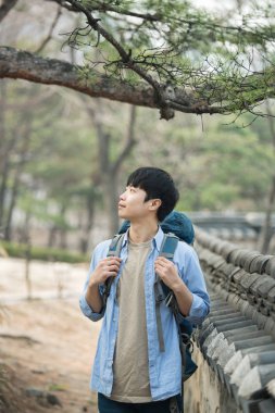 Kore geleneksel evde bir sırt çantasıyla yolculuk yapan bir genç erkek.