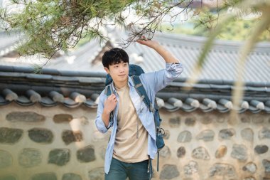 Kore geleneksel evde bir sırt çantasıyla yolculuk yapan bir genç erkek.