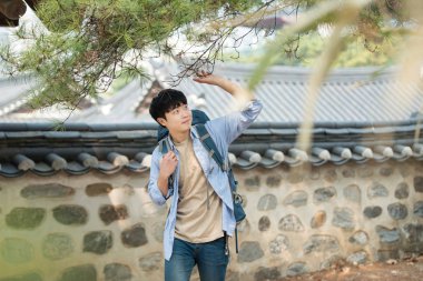 Kore geleneksel evde bir sırt çantasıyla yolculuk yapan bir genç erkek.