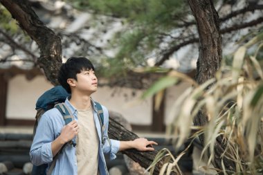 Kore geleneksel evde bir sırt çantasıyla yolculuk yapan bir genç erkek.