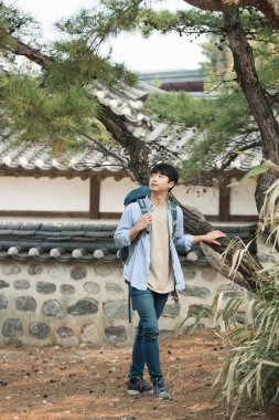 Kore geleneksel evde bir sırt çantasıyla yolculuk yapan bir genç erkek.