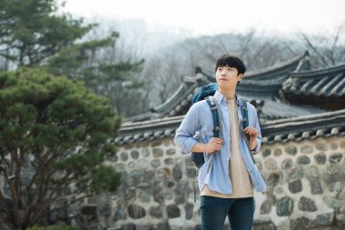 Kore geleneksel evde bir sırt çantasıyla yolculuk yapan genç erkek.