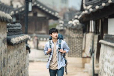 Kore geleneksel evde bir sırt çantasıyla yolculuk yapan genç erkek.