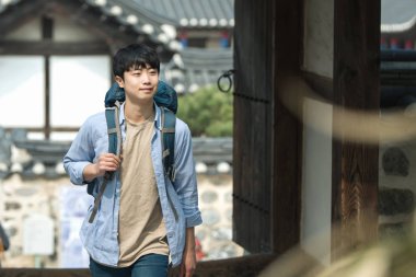 Kore geleneksel evde bir sırt çantasıyla yolculuk yapan genç erkek.