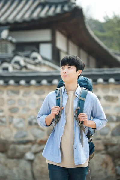 Kore geleneksel evde bir sırt çantasıyla yolculuk yapan bir genç erkek.