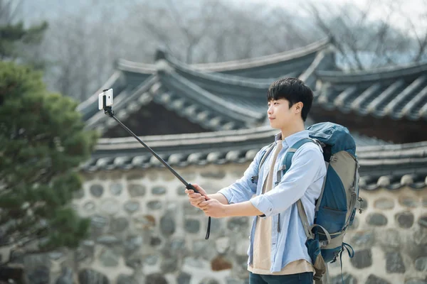 一位前往韩国的年轻人正在用他的智能手机拍照 — 图库照片