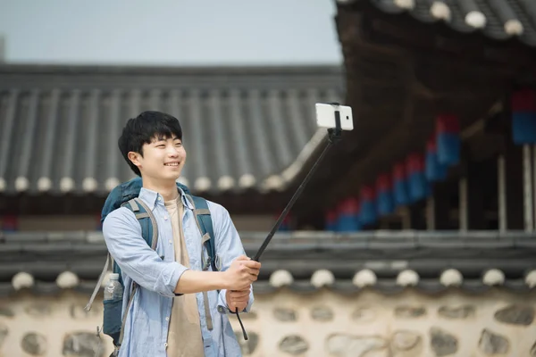 一位前往韩国的年轻人正在用他的智能手机拍照 — 图库照片