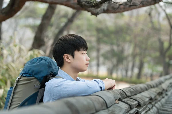 Kore geleneksel evde bir sırt çantasıyla yolculuk yapan bir genç erkek.