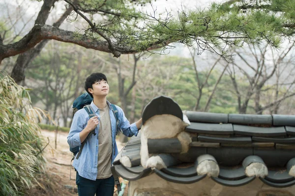 Kore geleneksel evde bir sırt çantasıyla yolculuk yapan bir genç erkek.