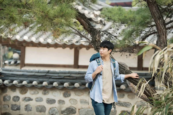 Kore geleneksel evde bir sırt çantasıyla yolculuk yapan bir genç erkek.