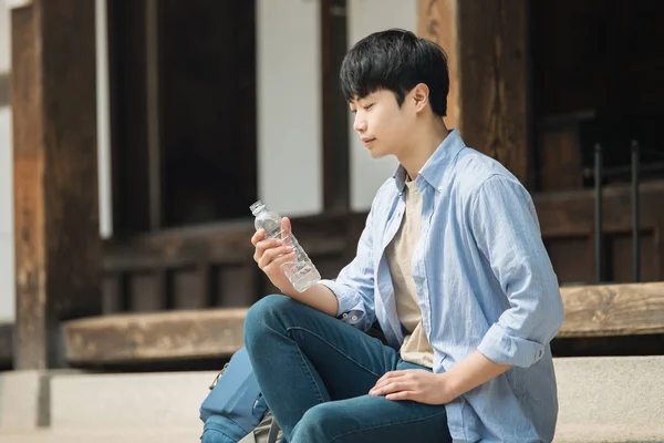 Νεαρός άνδρας ταξιδεύει στην Κορέα λαμβάνοντας ένα υπόλοιπο με ένα μπουκάλι νερό. — Φωτογραφία Αρχείου